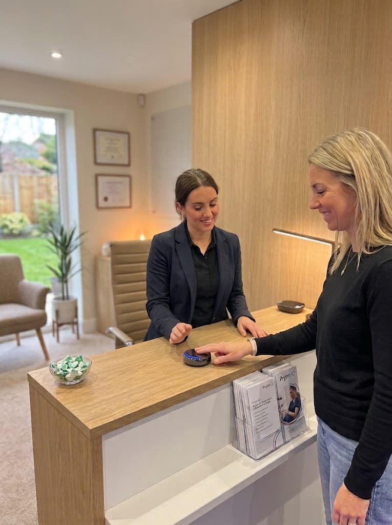 A person placing a fingertip on the Prysm iO scanner at a clinic reception desk